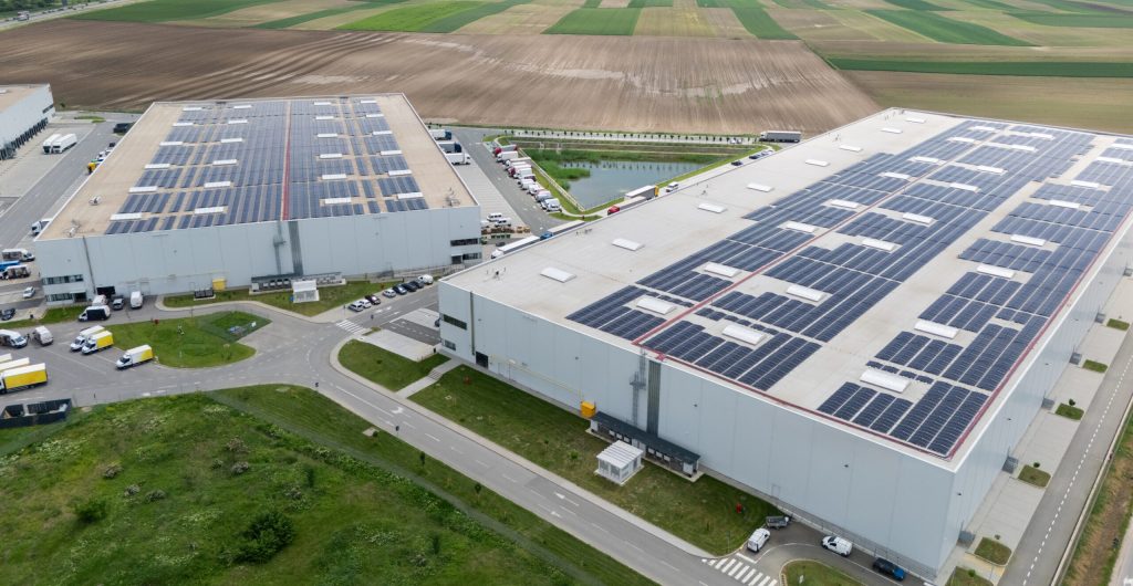 Logistics centers with solar panels on roofs. Aerial view. Drone point of view.